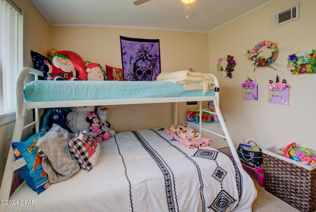 carpeted bedroom featuring a ceiling fan, visible vents, and crown molding