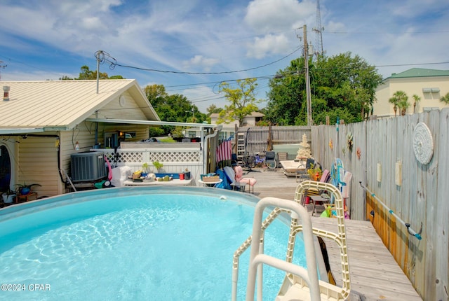 view of swimming pool with a fenced in pool, cooling unit, a fenced backyard, and a wooden deck