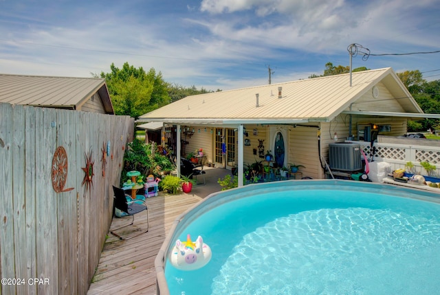 outdoor pool featuring central air condition unit, fence, and a deck