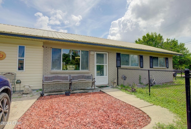 view of front of house featuring metal roof, brick siding, and fence