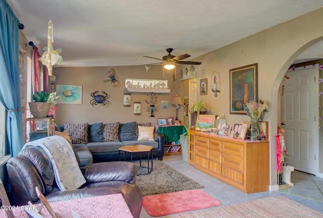 tiled living room with a ceiling fan and arched walkways