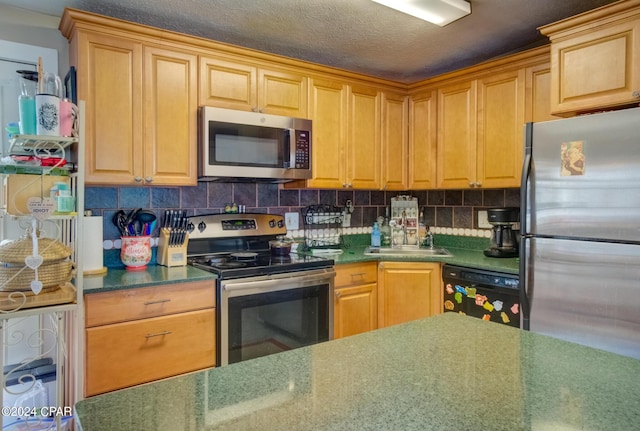 kitchen featuring stainless steel appliances, a sink, backsplash, and a textured ceiling