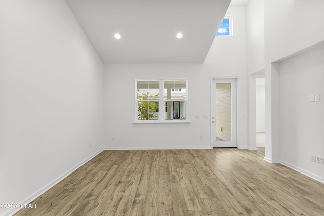 unfurnished living room with light hardwood / wood-style floors and high vaulted ceiling