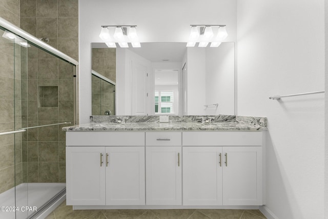 bathroom with tile patterned flooring, a shower with shower door, and vanity