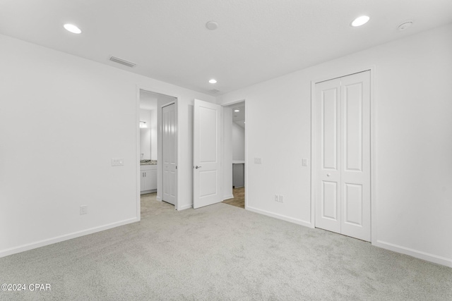 unfurnished bedroom featuring a closet and light colored carpet