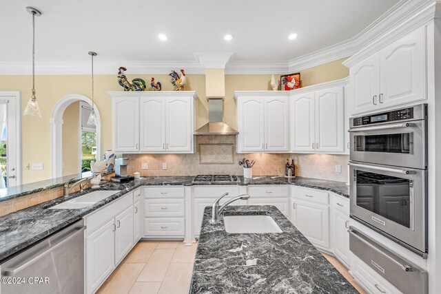 kitchen featuring stainless steel appliances, sink, wall chimney exhaust hood, and white cabinets