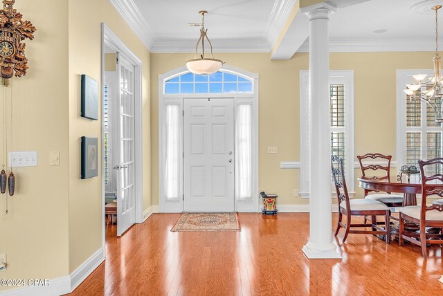 entrance foyer with decorative columns, light hardwood / wood-style floors, a notable chandelier, and ornamental molding