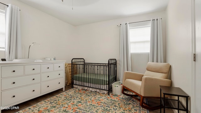 bedroom with a crib and dark hardwood / wood-style floors