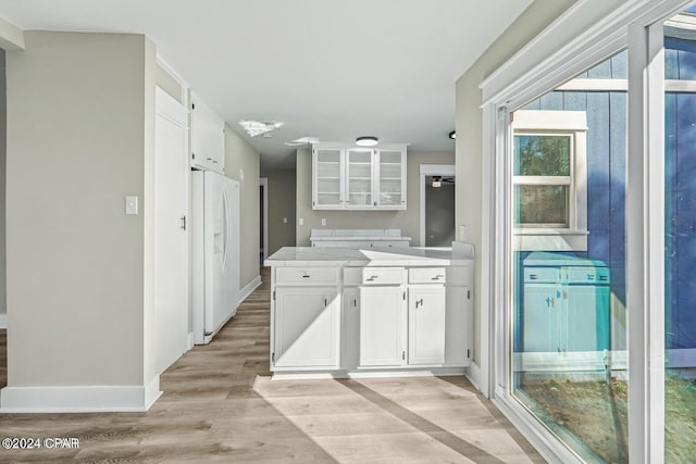 kitchen with white fridge with ice dispenser, light hardwood / wood-style flooring, and white cabinetry