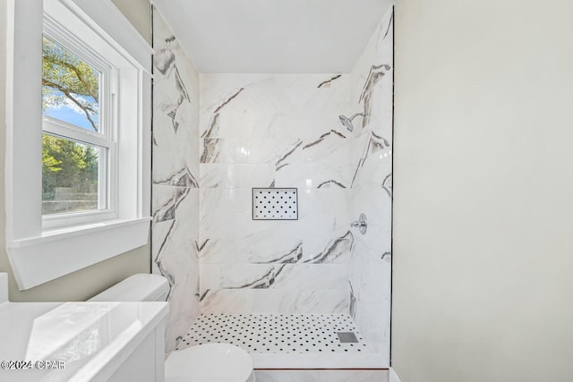 bathroom with a tile shower and toilet