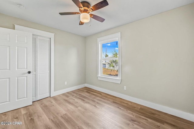 unfurnished bedroom featuring ceiling fan, light wood-type flooring, and a closet