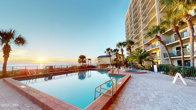 pool at dusk with a water view and a patio