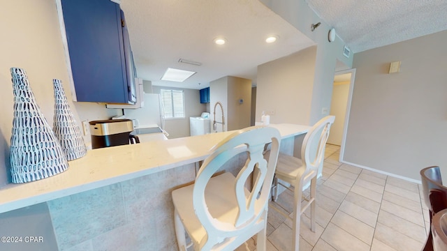 kitchen featuring tile patterned floors, blue cabinetry, sink, kitchen peninsula, and a textured ceiling