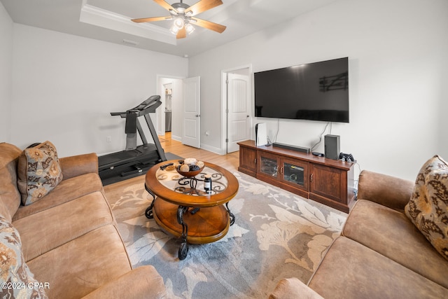 living room featuring light hardwood / wood-style floors, a tray ceiling, and ceiling fan