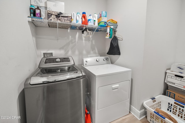 clothes washing area with washer and clothes dryer and light hardwood / wood-style floors