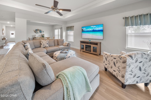 living room featuring ceiling fan, a tray ceiling, crown molding, and light hardwood / wood-style floors