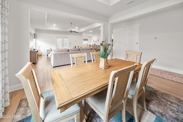 dining room with ceiling fan, light hardwood / wood-style flooring, and a raised ceiling