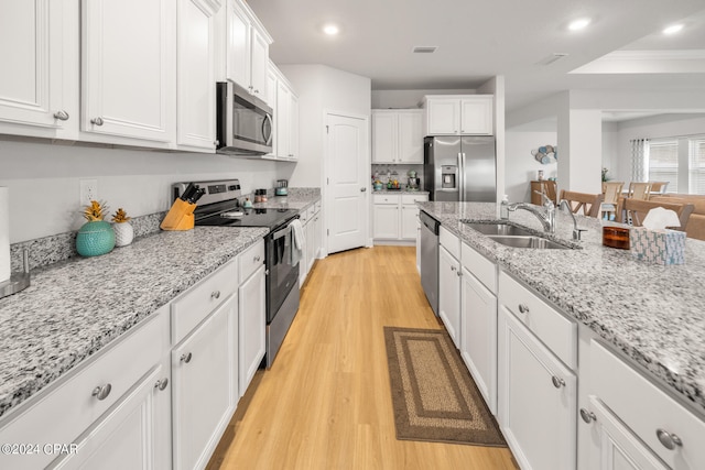 kitchen featuring appliances with stainless steel finishes, light wood-type flooring, crown molding, and white cabinets