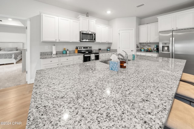 kitchen featuring appliances with stainless steel finishes, sink, white cabinetry, and a breakfast bar