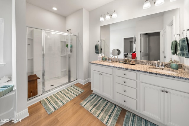 bathroom with wood-type flooring, vanity, and a shower with shower door