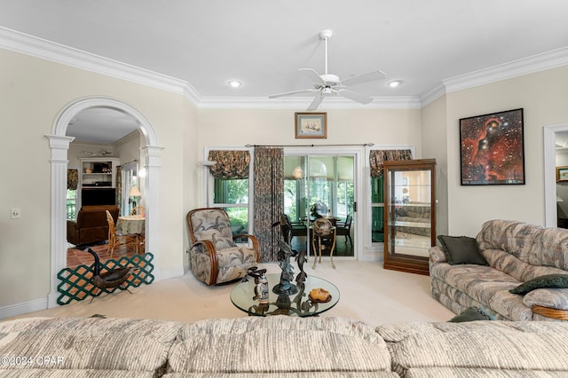 living room with light carpet, decorative columns, ceiling fan, and crown molding