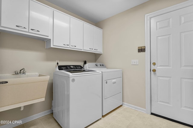 laundry room with cabinets, light tile patterned flooring, washer and dryer, and sink