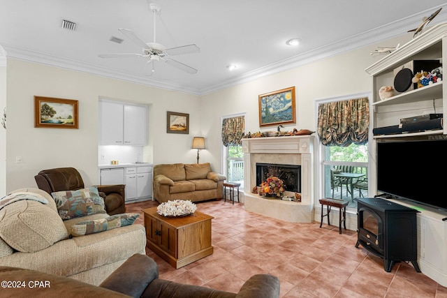 living room featuring ceiling fan, ornamental molding, plenty of natural light, and a premium fireplace