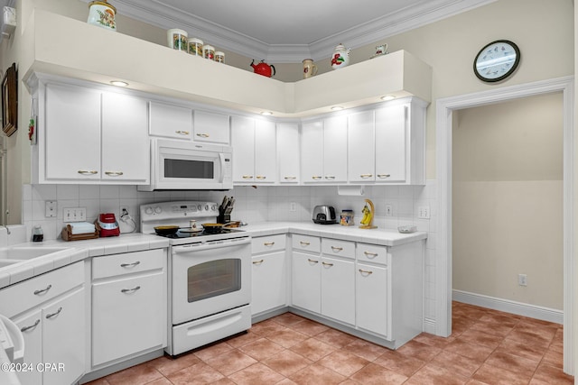 kitchen with crown molding, white appliances, white cabinetry, and tile countertops