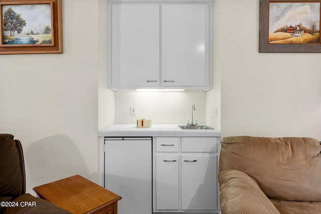 bar with white cabinetry, tile counters, and sink