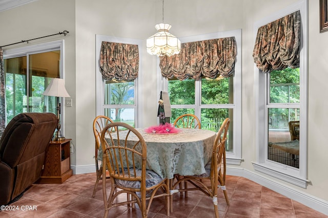 tiled dining room featuring an inviting chandelier and a healthy amount of sunlight