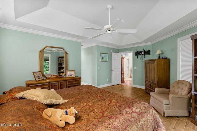 bedroom with light hardwood / wood-style floors, ceiling fan, and a tray ceiling