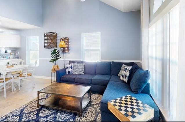 living room featuring a towering ceiling, tile patterned flooring, and plenty of natural light