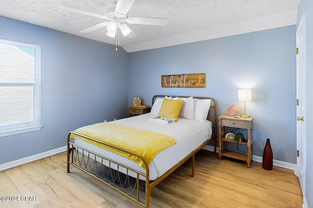 bedroom with light hardwood / wood-style flooring, ceiling fan, and a textured ceiling