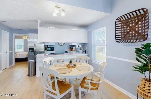 dining area featuring an inviting chandelier, light hardwood / wood-style floors, and a textured ceiling