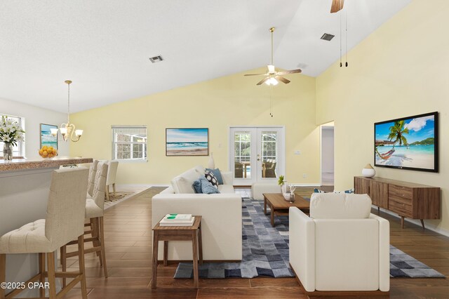 living room featuring french doors, dark wood-type flooring, high vaulted ceiling, and ceiling fan with notable chandelier