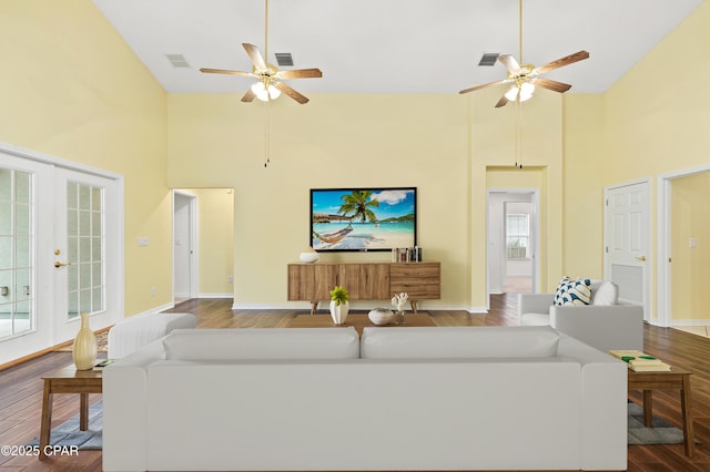 living room featuring ceiling fan, french doors, dark wood-type flooring, and a high ceiling