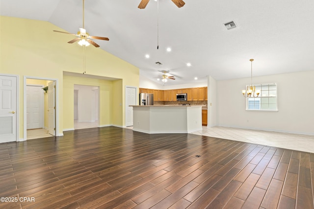 unfurnished living room featuring ceiling fan with notable chandelier and high vaulted ceiling