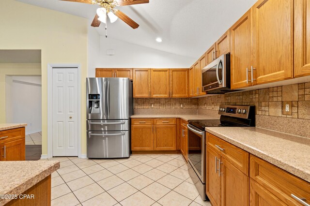 kitchen featuring sink, hanging light fixtures, vaulted ceiling, light tile patterned floors, and appliances with stainless steel finishes