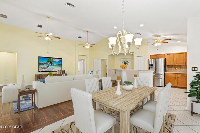 tiled dining room with high vaulted ceiling and a notable chandelier