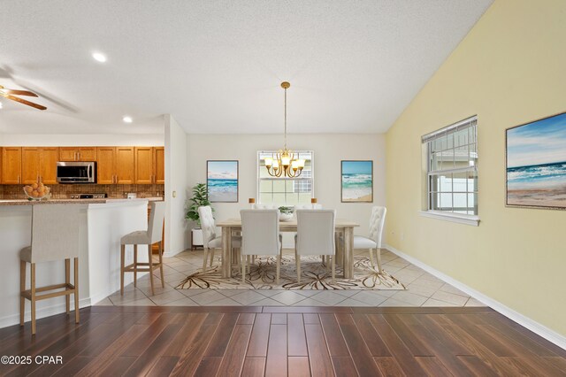 unfurnished dining area featuring hardwood / wood-style flooring, plenty of natural light, ceiling fan with notable chandelier, and lofted ceiling