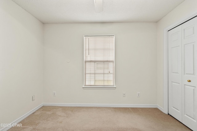 unfurnished bedroom with a textured ceiling, light colored carpet, and ceiling fan