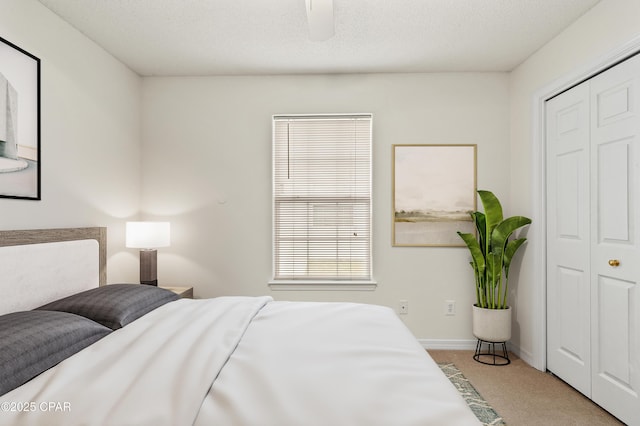 bedroom with ceiling fan, a closet, light carpet, and a textured ceiling