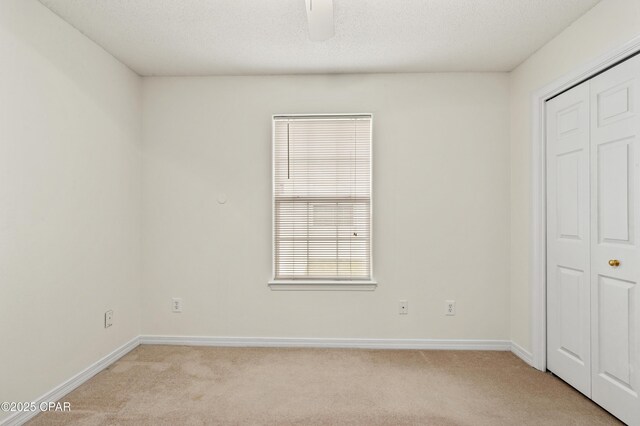 unfurnished bedroom with a closet, a textured ceiling, and light colored carpet