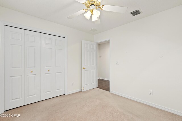 unfurnished bedroom with a textured ceiling, a closet, ceiling fan, and light colored carpet