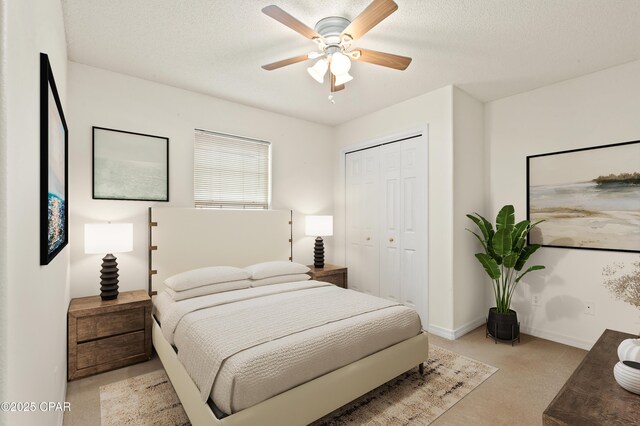 bedroom with ceiling fan, light colored carpet, a textured ceiling, and a closet