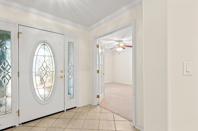 foyer entrance featuring ceiling fan, ornamental molding, light tile patterned floors, and a textured ceiling