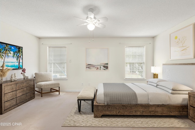 carpeted bedroom featuring ceiling fan and a textured ceiling