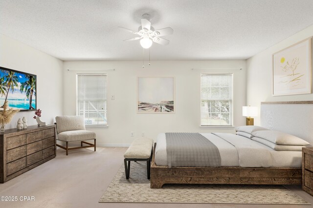 carpeted bedroom featuring ceiling fan and a textured ceiling