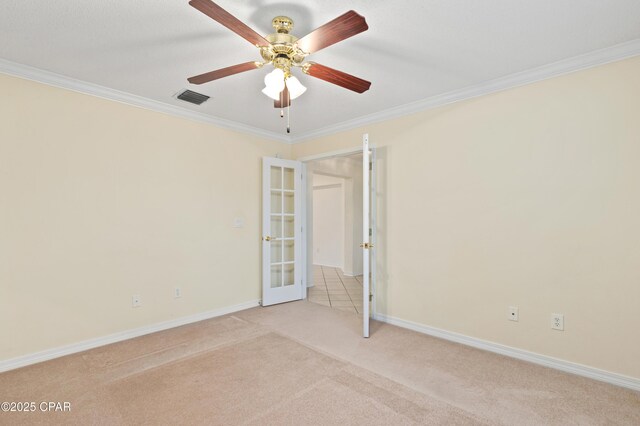 carpeted spare room featuring ceiling fan, ornamental molding, and french doors