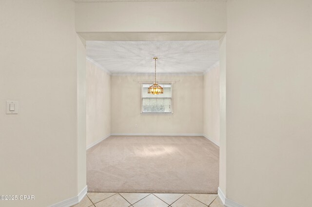 carpeted empty room featuring a textured ceiling, crown molding, and an inviting chandelier